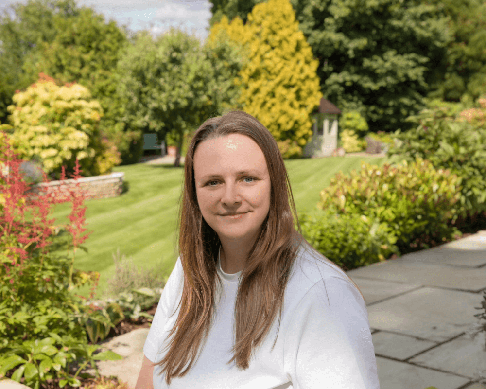 Pauline staying in a garden with trees in the background